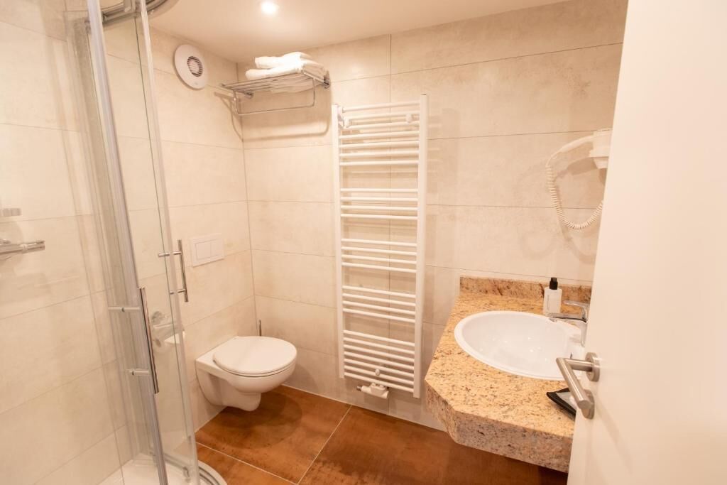 Une salle de bain dotée d’une douche à parois de verre, de toilettes, d’un porte-serviettes et d’un lavabo avec un plan de travail en granit.