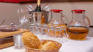 A table with a basket of bread, a bottle of champagne, and several glasses and pitchers.
