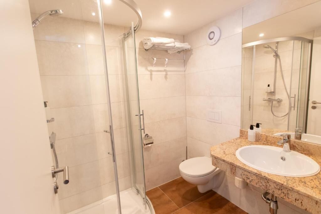 Ein modernes Badezimmer mit einer Duschkabine, einer weißen Toilette und einem Waschbecken mit Granitplatte.