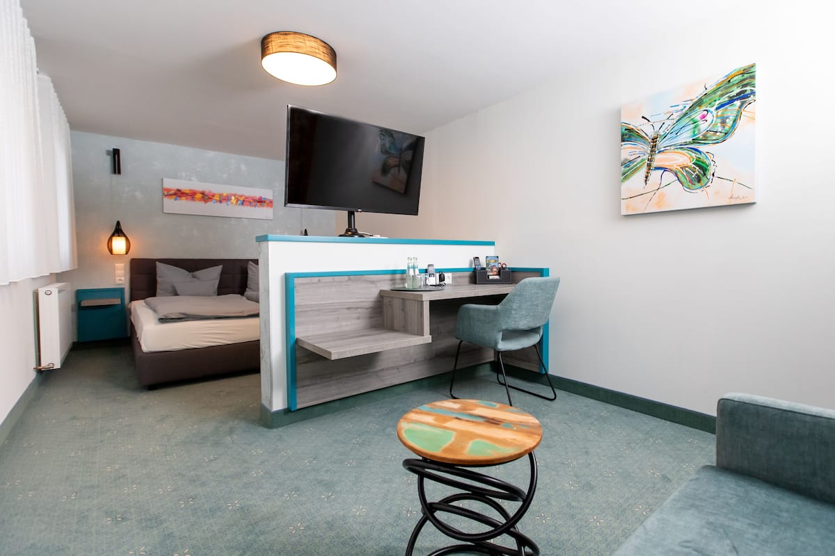 Une petite chambre comprenant un lit, un bureau, une chaise et un téléviseur.