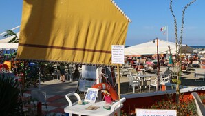 A beachside market with a yellow sail, a signboard for 'Giardino', and outdoor seating. - Hotel Residenza Giardino (Bellaria-Igea Marina)