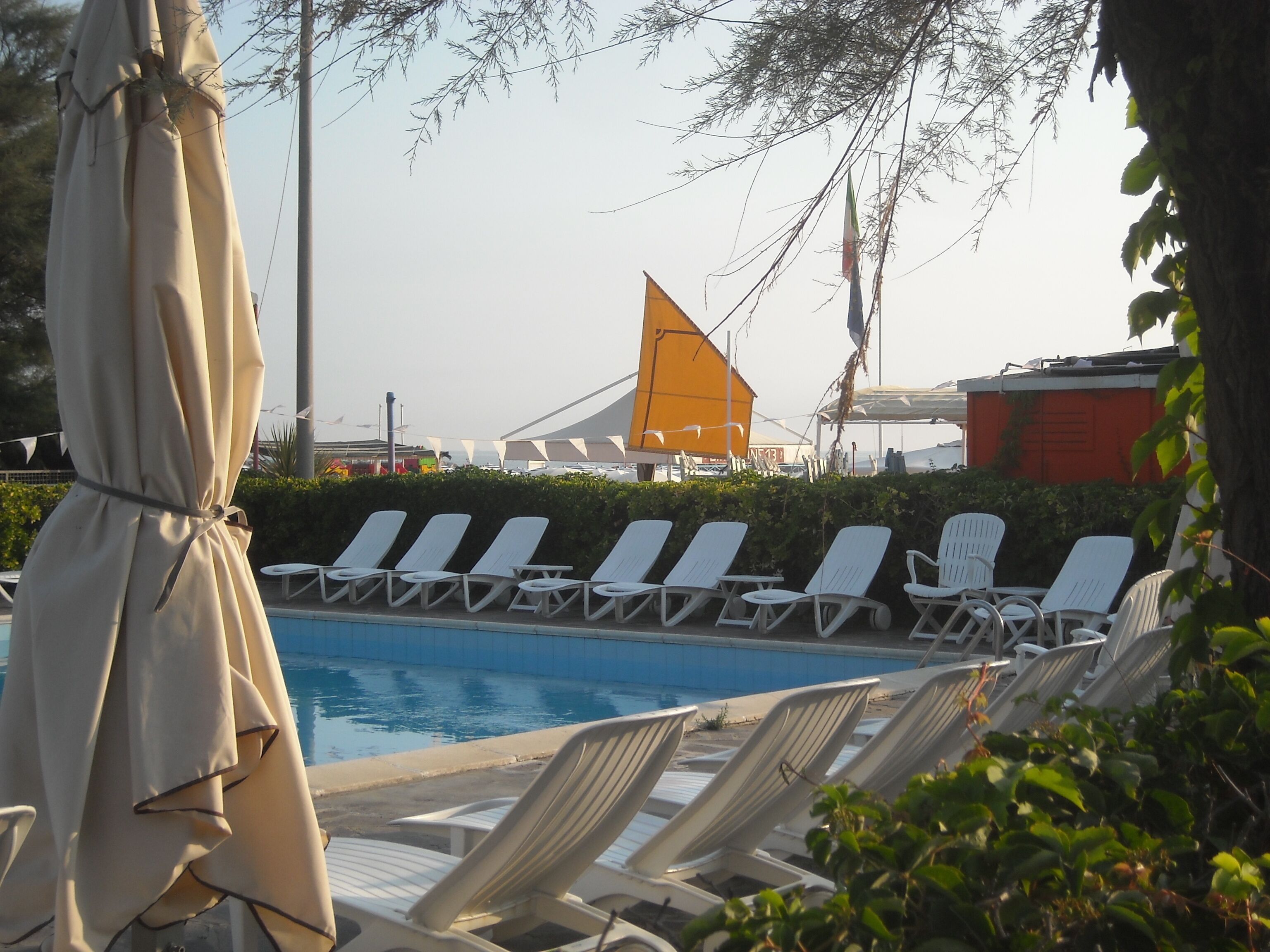 A poolside area with lounge chairs and a covered umbrella.