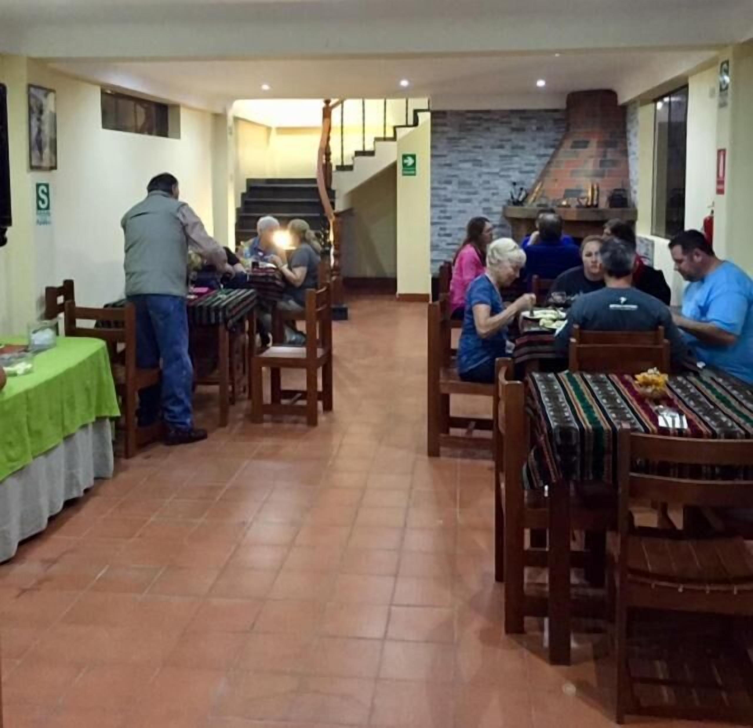 A restaurant with wooden tables and chairs, a staircase, and a tiled floor.