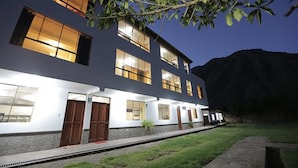 A modern two-story building with multiple windows and doors, a well-maintained lawn, and a mountain in the background. - Casa San Vicente Yucay (Yucay)