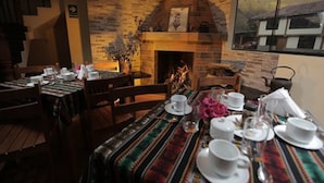 A dining area with a brick fireplace, wooden tables, and chairs. - Casa San Vicente Yucay (Yucay)