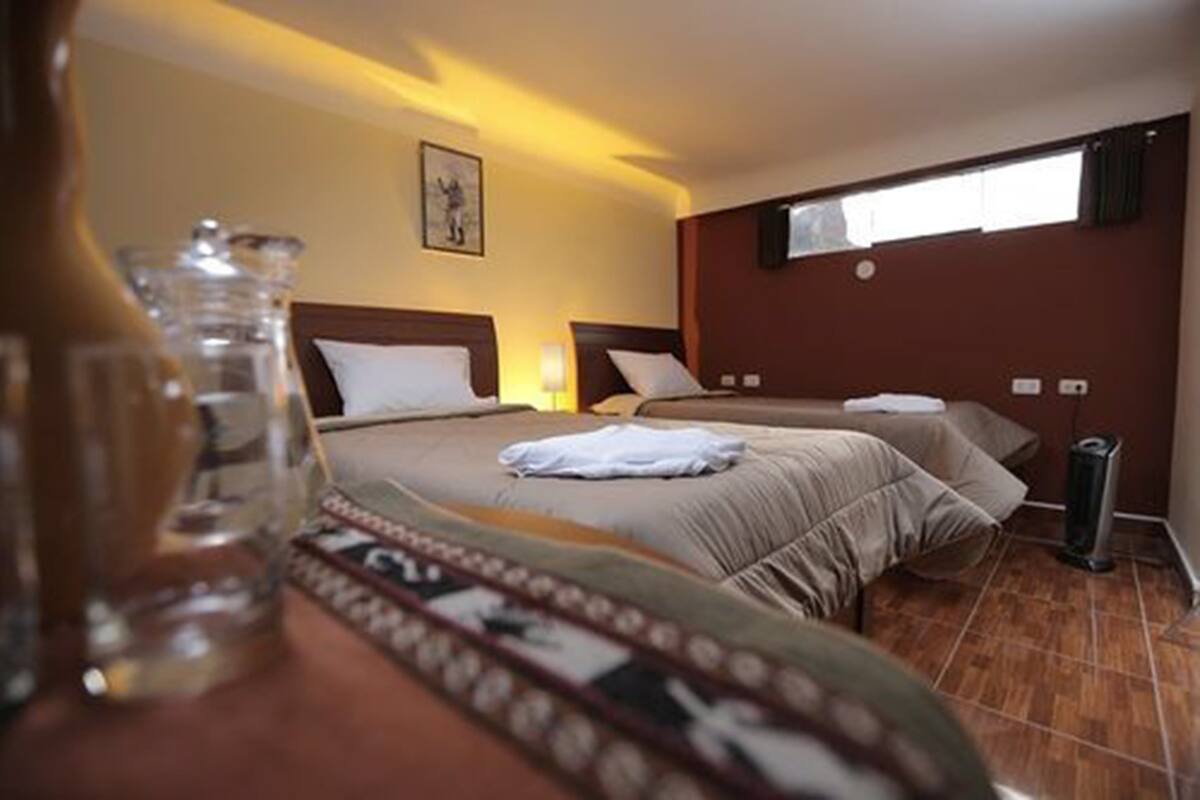 Une chambre d’hôtel avec deux lits, une fenêtre et une poubelle.
