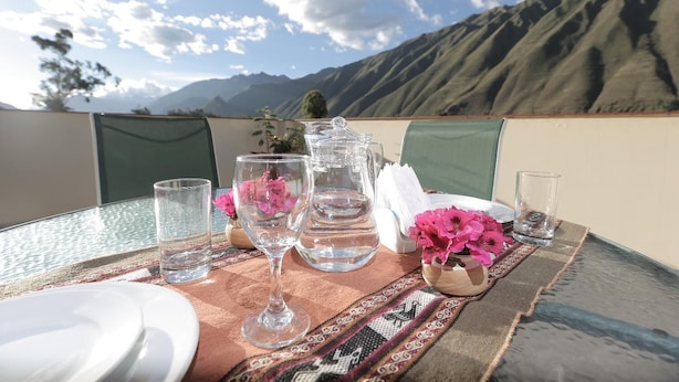 A table set with glasses, a pitcher, and a plate, with a mountain view in the background. - Casa San Vicente Yucay (Yucay)