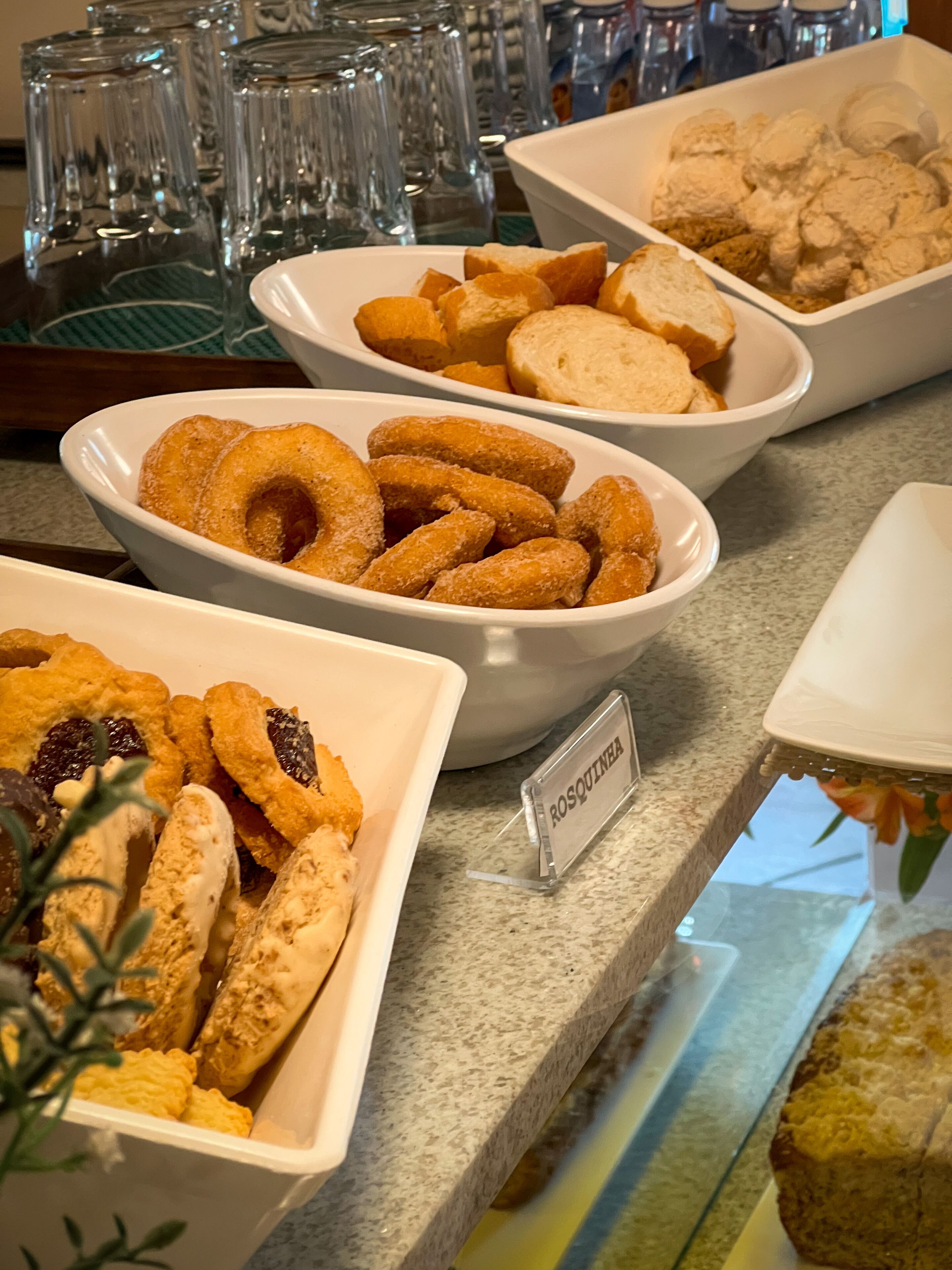 Un bufé con diferentes opciones de comida, incluyendo rosquillas, pasteles y un cartel que dice "Rosquinha".