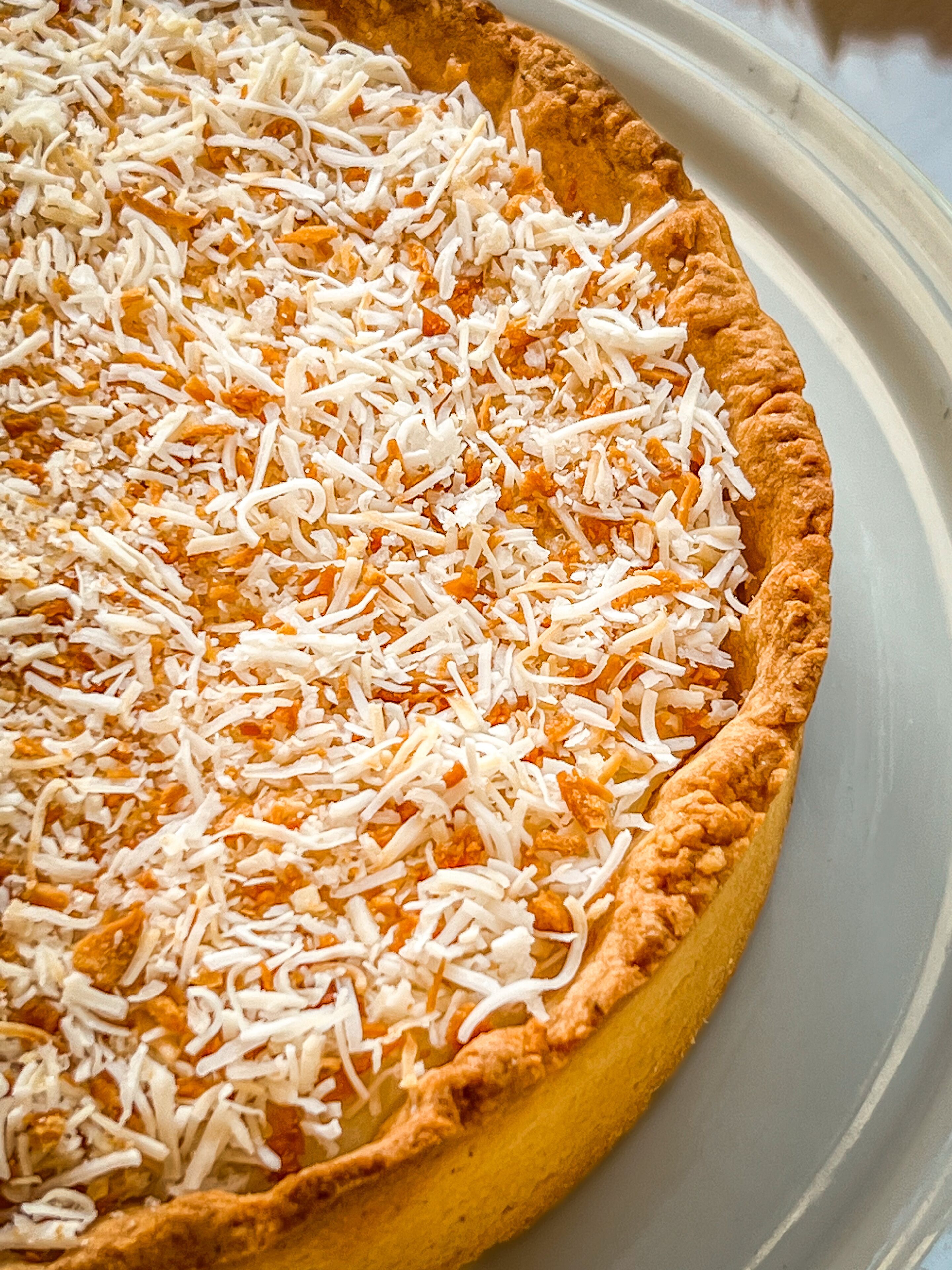 Una tarta de queso con una costra dorada y queso rallado por encima.