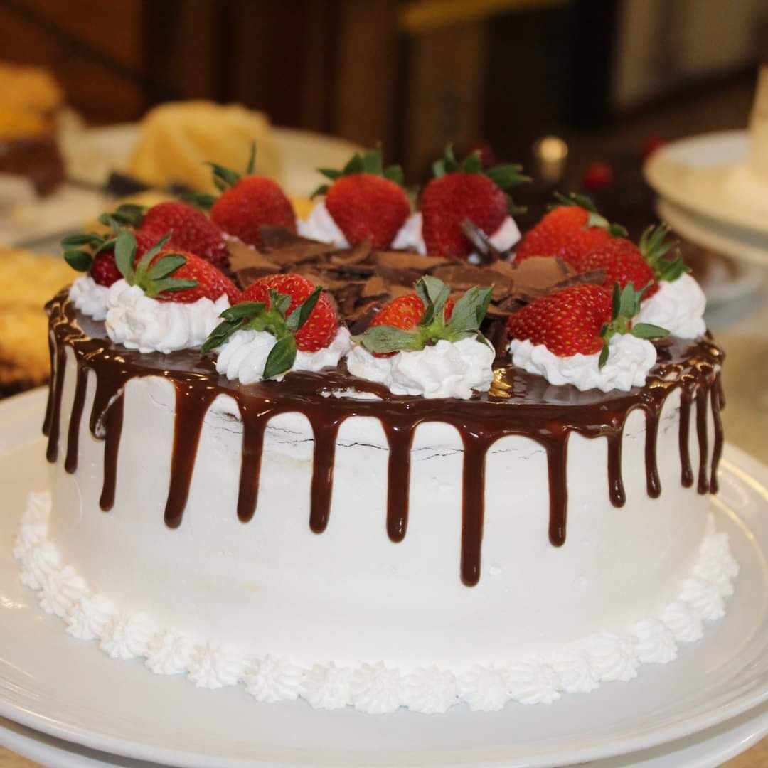 Un gâteau aux fraises, garni de crème fouettée, présenté sur une assiette blanche.