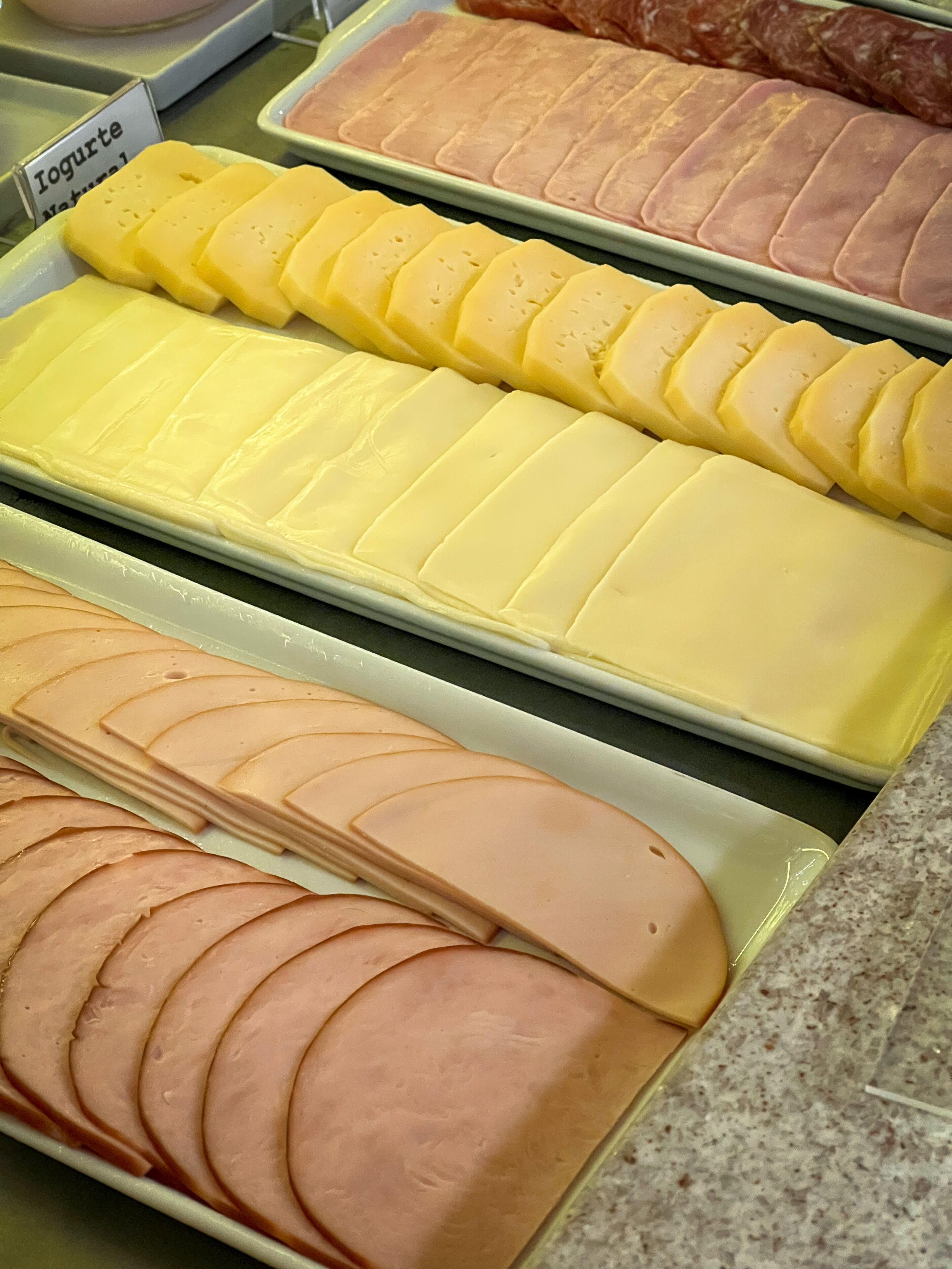 Vitrine com fatias de queijos e embutidos em uma delicatessen.