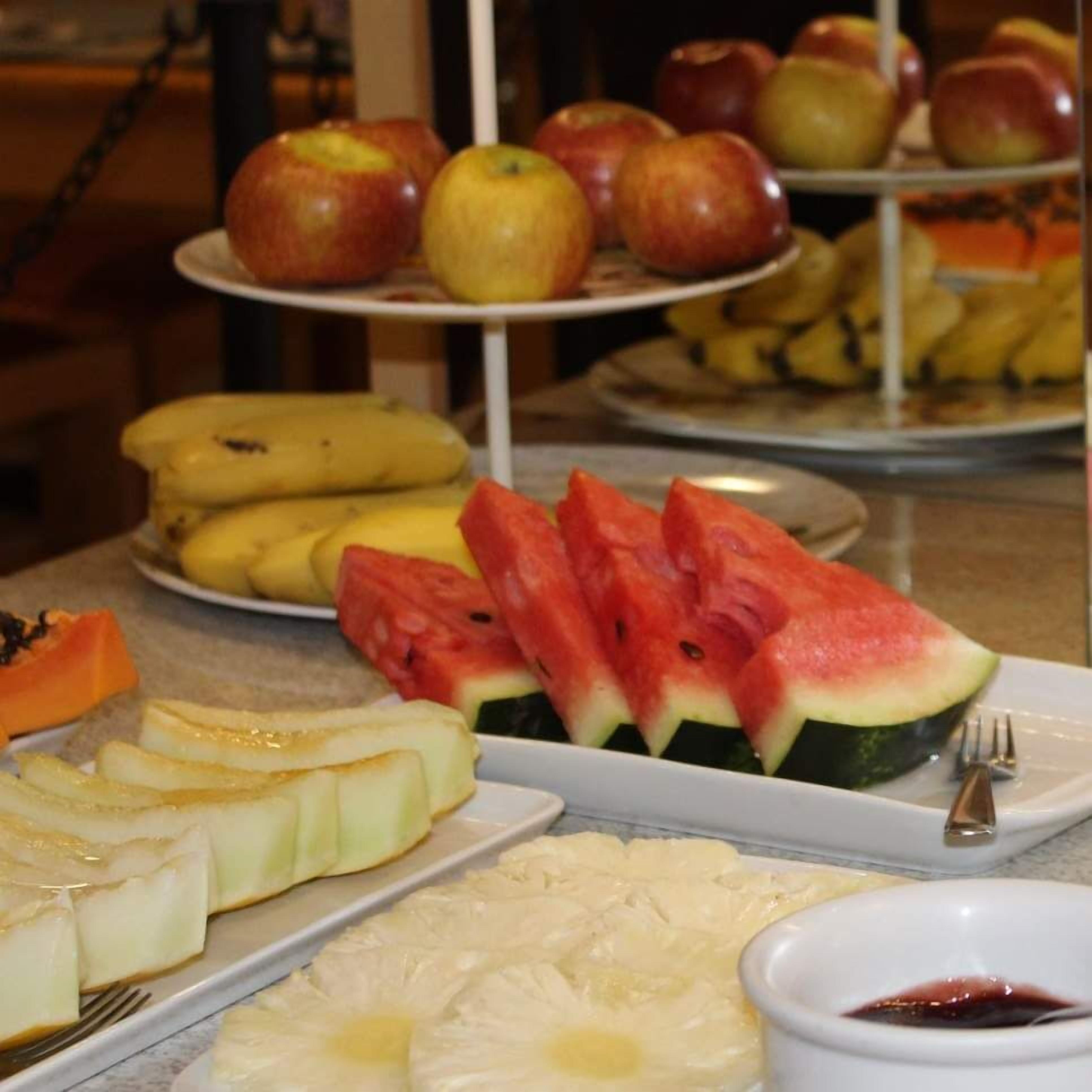 A breakfast buffet with various fruits and a plate of scrambled eggs.