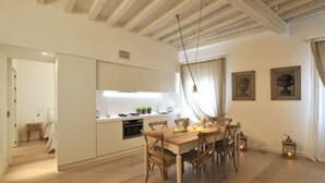 Una cocina moderna con armarios blancos, una mesa de comedor de madera y una araña.