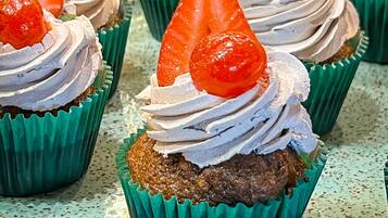 Cupcakes with whipped cream and strawberries on a tray.