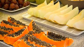 A buffet with various fruits and vegetables, including grapes, pears, and papaya.
