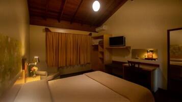 Una camera d'albergo con un letto, una scrivania, una televisione e una finestra con tende.