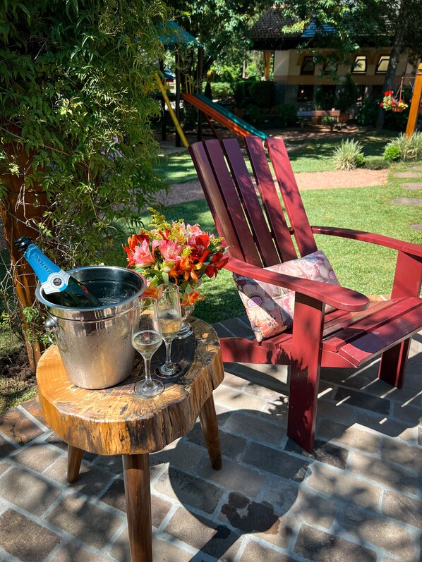 Un patio con una mesa de madera, un balde de metal y una silla roja.