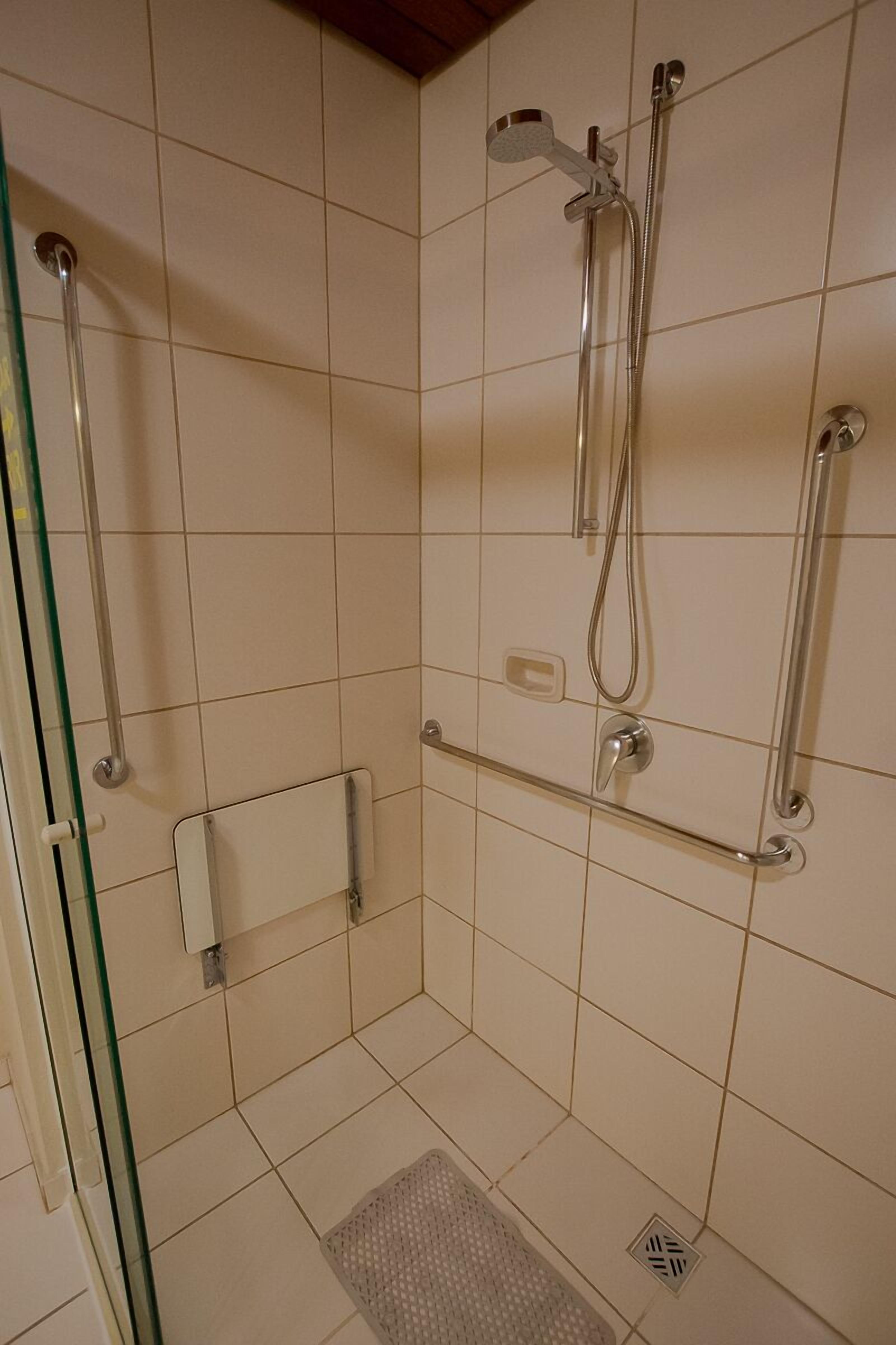 Un espace douche doté d’une porte en verre, d’un pommeau de douche à main et d’un flexible de douche.