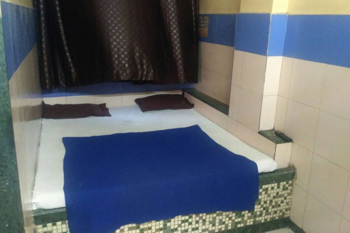 Una habitación pequeña y estrecha con cama, una banca y pared de azulejos.