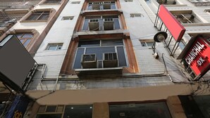 Un edificio de varios pisos con ventanas amplias y un letrero rojo a la derecha.