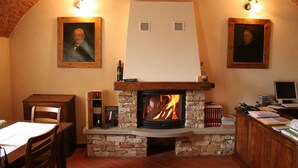 A cozy room with a fireplace, wooden furniture, and framed pictures on the walls. - Agriturismo La Virginia (Revello)