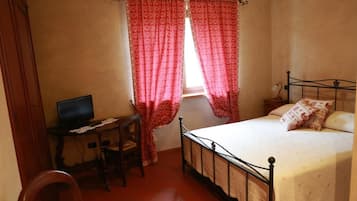 Un dormitori amb un llit, un escriptori i un ordinador, i cortines.