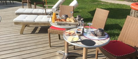 En uteplats med utemöbler, inklusive solstolar och ett bord uppdukat med mat och dryck.