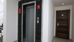 An elevator with a "No Smoking" sign, a digital display, and a door with a number plate. - Capital O 14043 Hotel Star Holiday (Chennai)