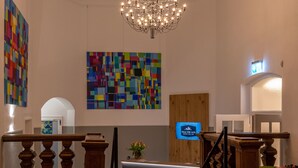 A reception area with a chandelier, a colorful abstract painting, and a sign for Villa von Satm. - Hotel Villa von Sayn (Rheinbreitbach)