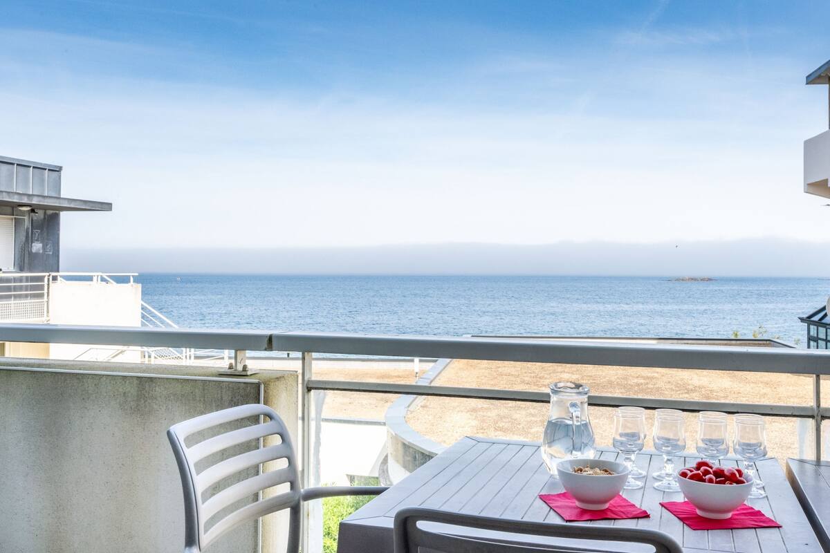 Un balcón con una mesa, sillas y vista al mar.