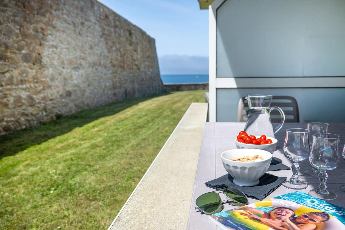 Una mesa al aire libre con una revista, una jarra y vasos.
