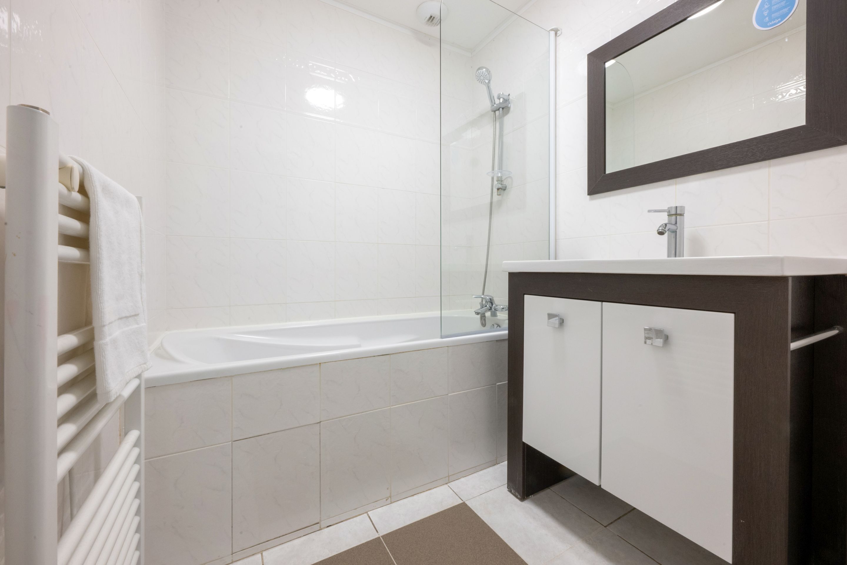A bathroom with a bathtub, a shower, a sink, and a mirror.
