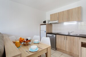 Una cocina compacta con armarios de madera, un microondas integrado y un lavavajillas.