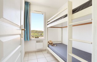Habitación con literas, ventana, puerta y radiador.