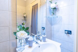A bathroom with a white sink, a mirror, and a shower area. - Terrazze Italiane City Center (Verona)