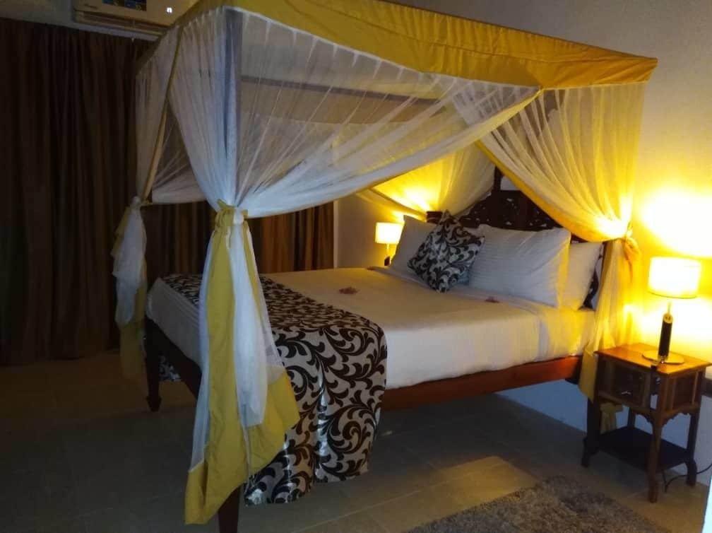 A bed with a canopy, bedside lamps, and a patterned bedspread.