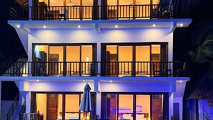 Un hotel a più piani con piscina, balconi e ambientazione tropicale.