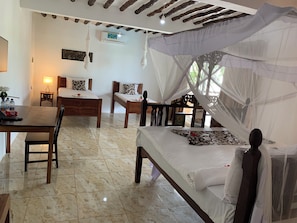 A bedroom with a bed, a desk, and a chair. There is a window with a view of greenery. - Isla Bonita Zanzibar Beach Resort (Matemwe)