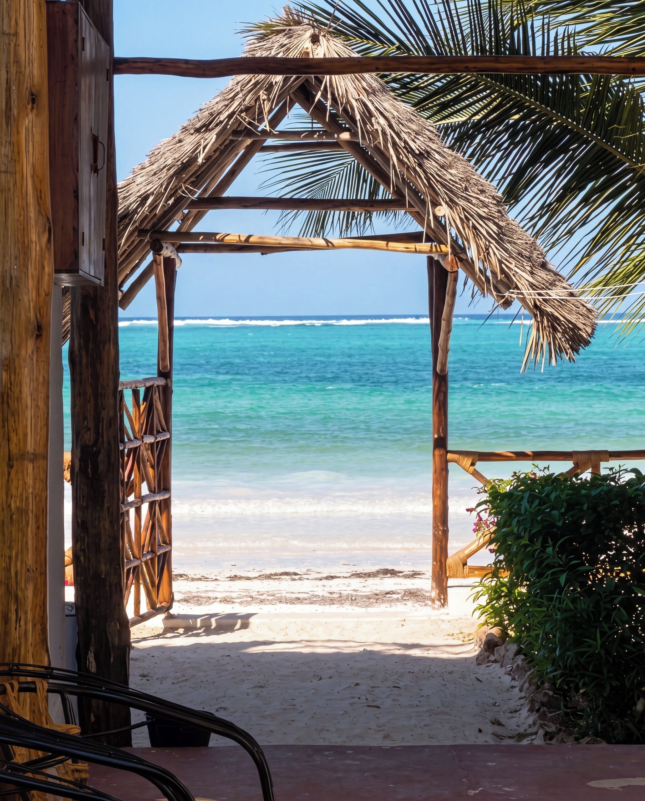 A beach view with a wooden structure and a thatched roof.