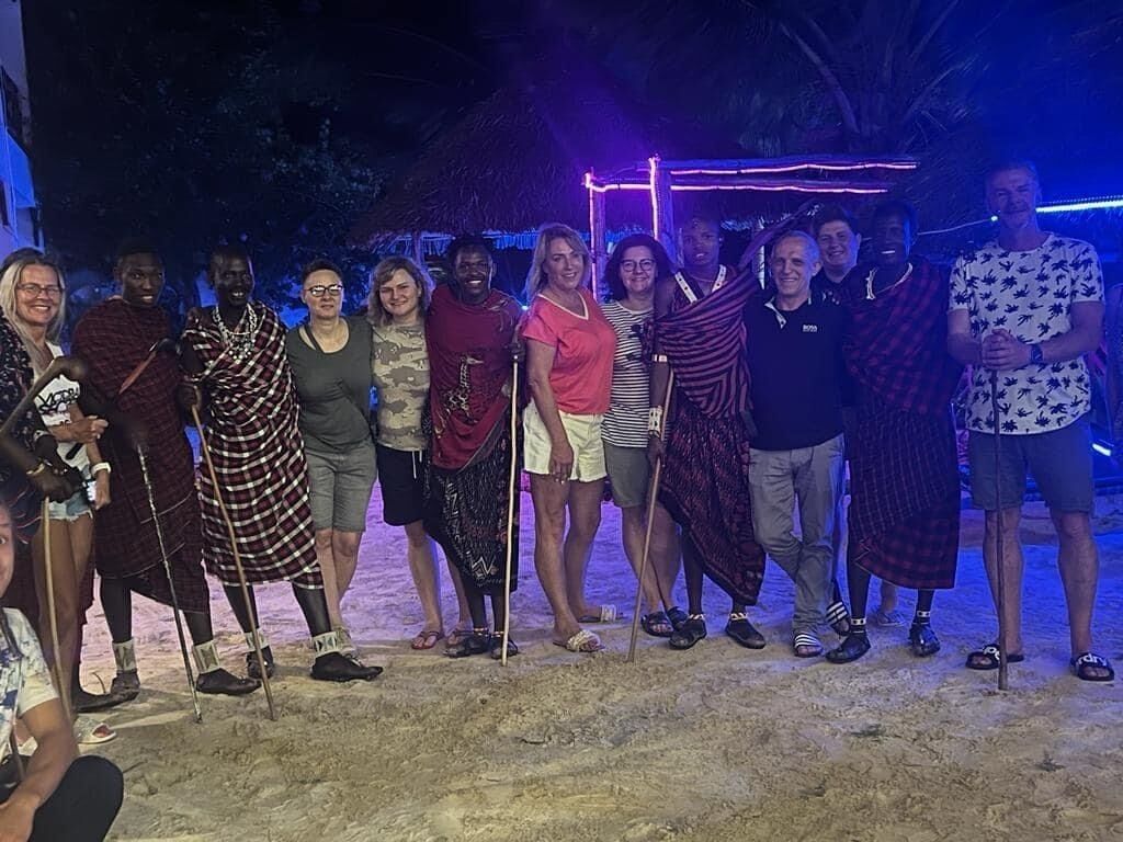 A group of people standing outdoors at night, some wearing traditional attire.
