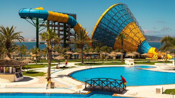 Ein großer Pool mit Wasserrutsche und im Hintergrund ein Riesenrad.