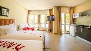 Ein Hotelzimmer mit zwei Betten, einem Fernseher, einer Küchenzeile und Blick ins Freie.