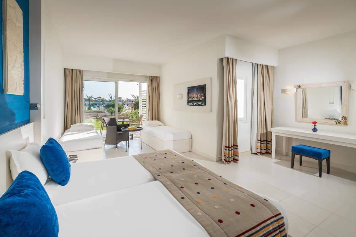 A hotel room with a bed, a desk, a chair, and a view of the outdoors.