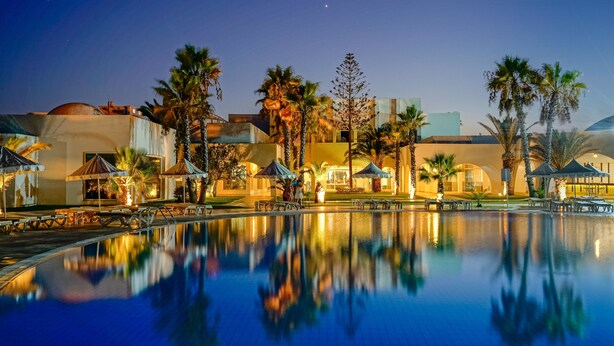 A nighttime resort pool with palm trees and a building with a dome roof. - Iliade Aqua Park Djerba (Djerba Midun)