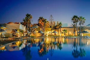 Una piscina cubierta, una piscina al aire libre, sombrillas, tumbonas