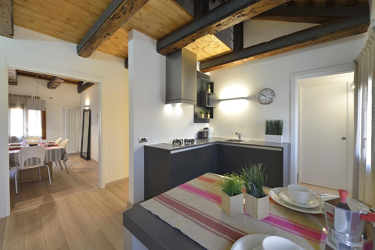 A modern kitchen with a central island, built-in appliances, and a dining area with a table and chairs.