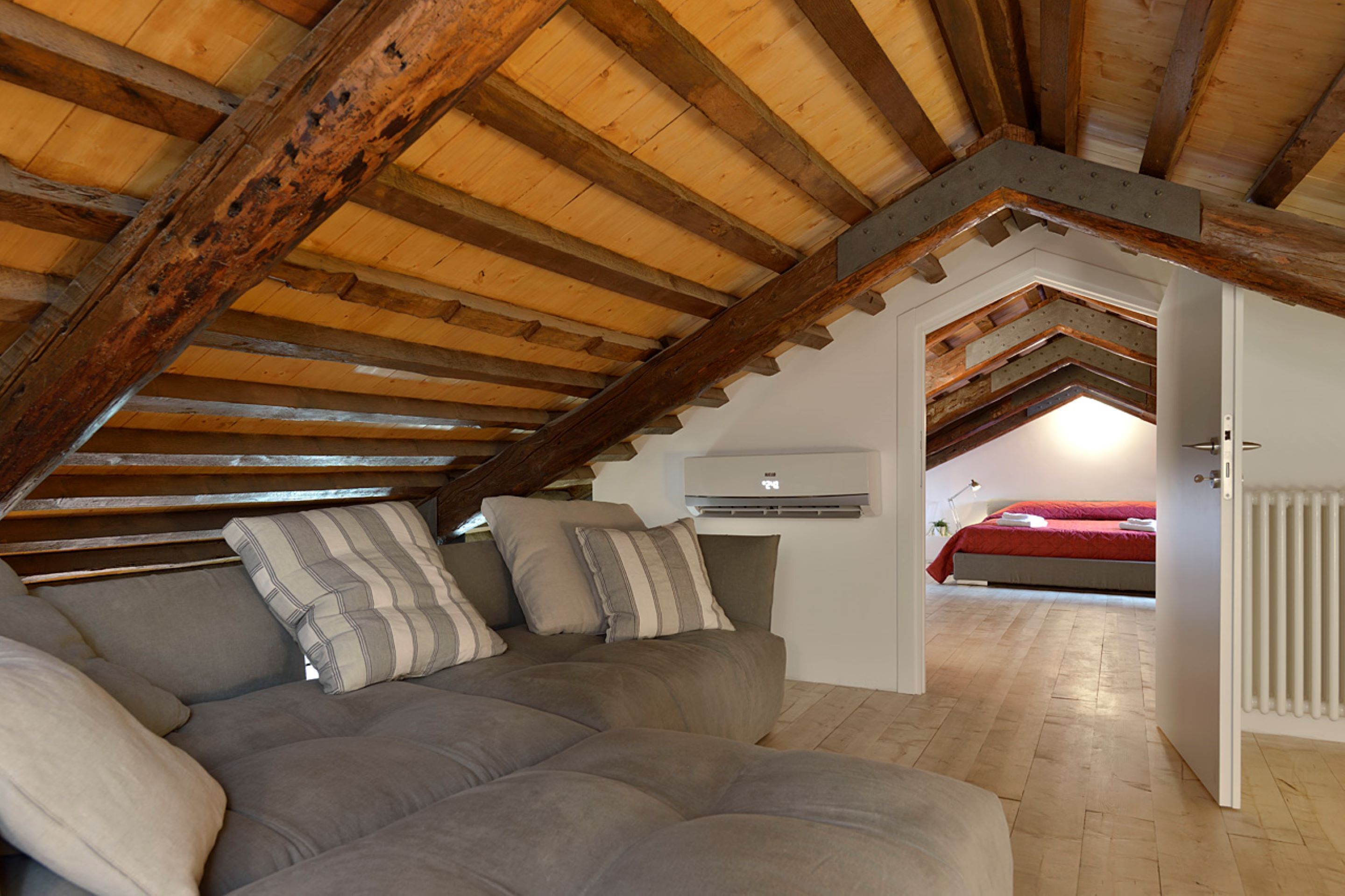 An attic bedroom with a sloped ceiling, a built-in bed, and a large window.