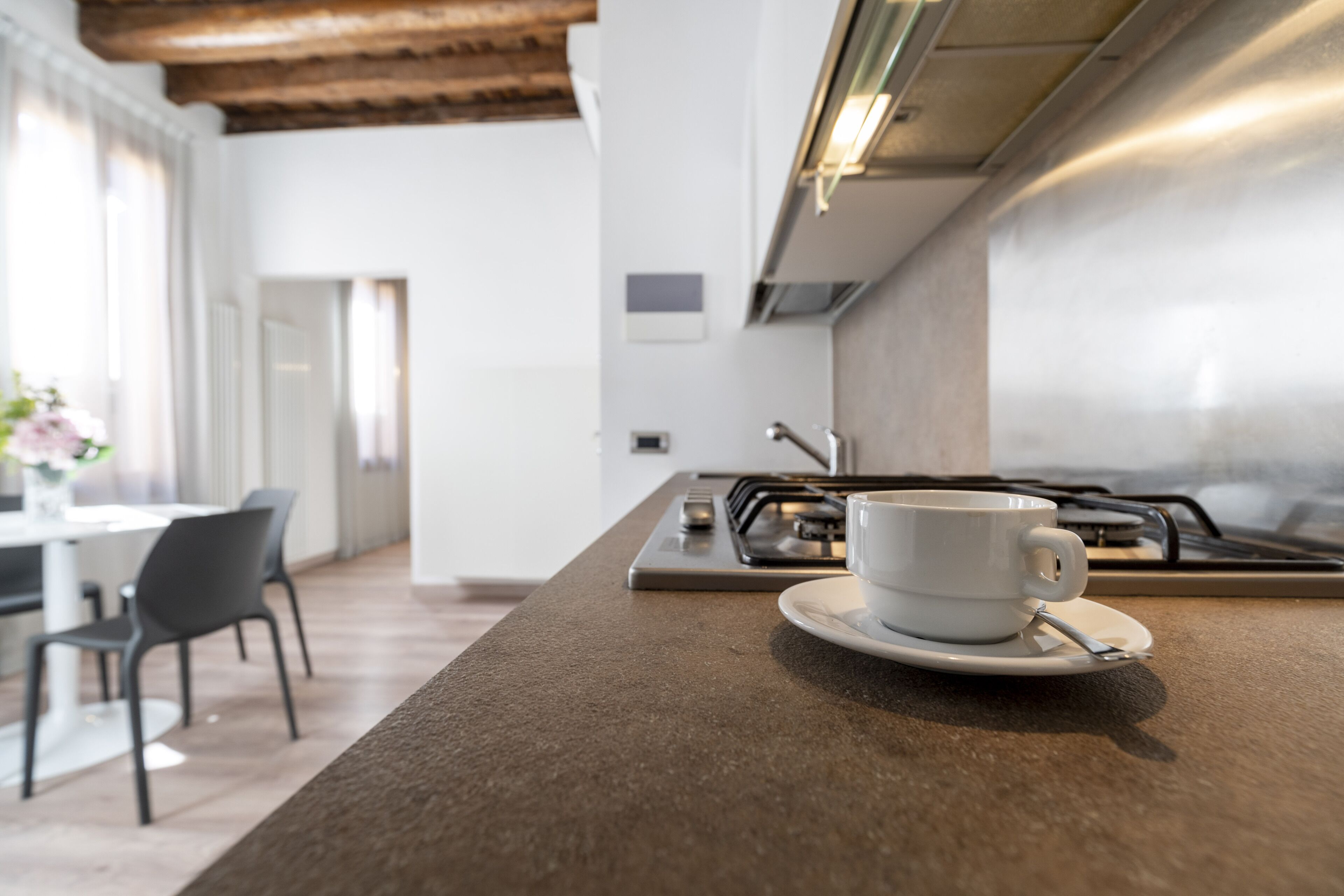 Een moderne keuken met een koffiekop op het aanrecht, een eethoek met stoelen en een uitzicht op de eetkamer.