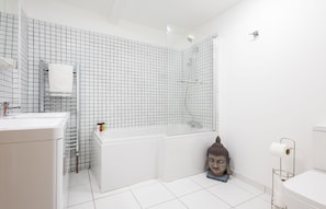 Une salle de bain moderne avec un mur orné d’un motif à carreaux, un lavabo blanc, une baignoire et des toilettes.
