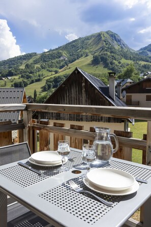 Une table dressée à l’extérieur, avec vue sur les montagnes, une clôture en bois et une table en métal.